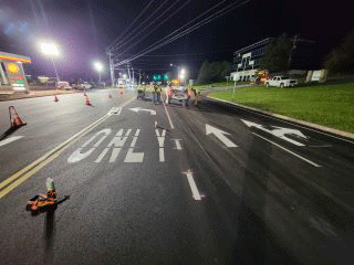 Crews installing pavement markings and line striping throughout the project area.