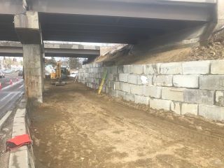 Crews work to install temporary structural reinforcement (shoring) under the east interstate bridge abutment to facilitate the installation of the retaining wall.