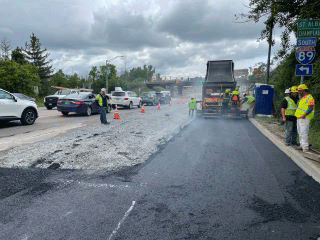 Crews paving disturbed segments of roadway with temporary pavement.