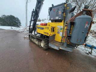 Drill used to bore into the ground to determine the location of ledge beneath the roadway surface.