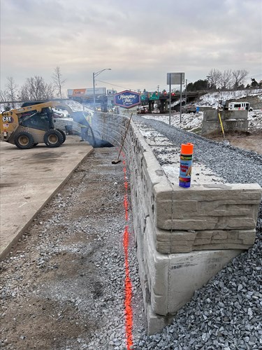 Crews pave along the base of the completed retaining wall located between The Lighthouse Restaurant parking lot and U.S. 2/7 in Colchester, VT.